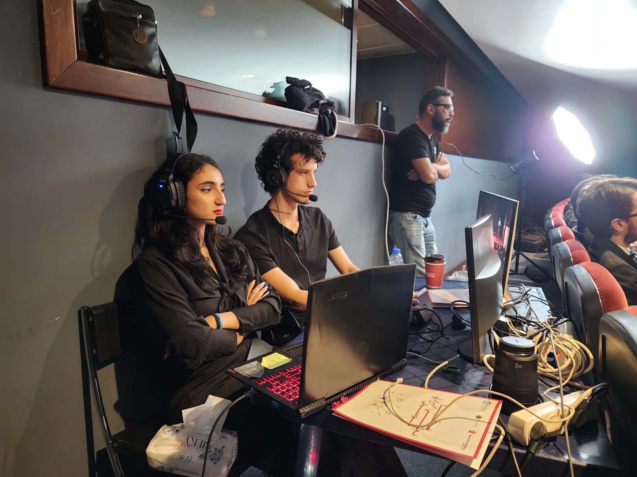 Crew members with headsets at the control desk at the back of a theatre