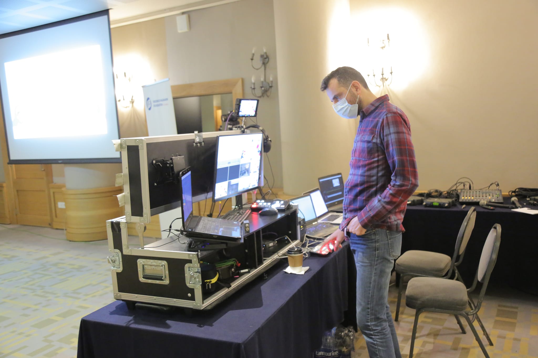 An engineer at the streaming rack and laptops at the side of a conference room