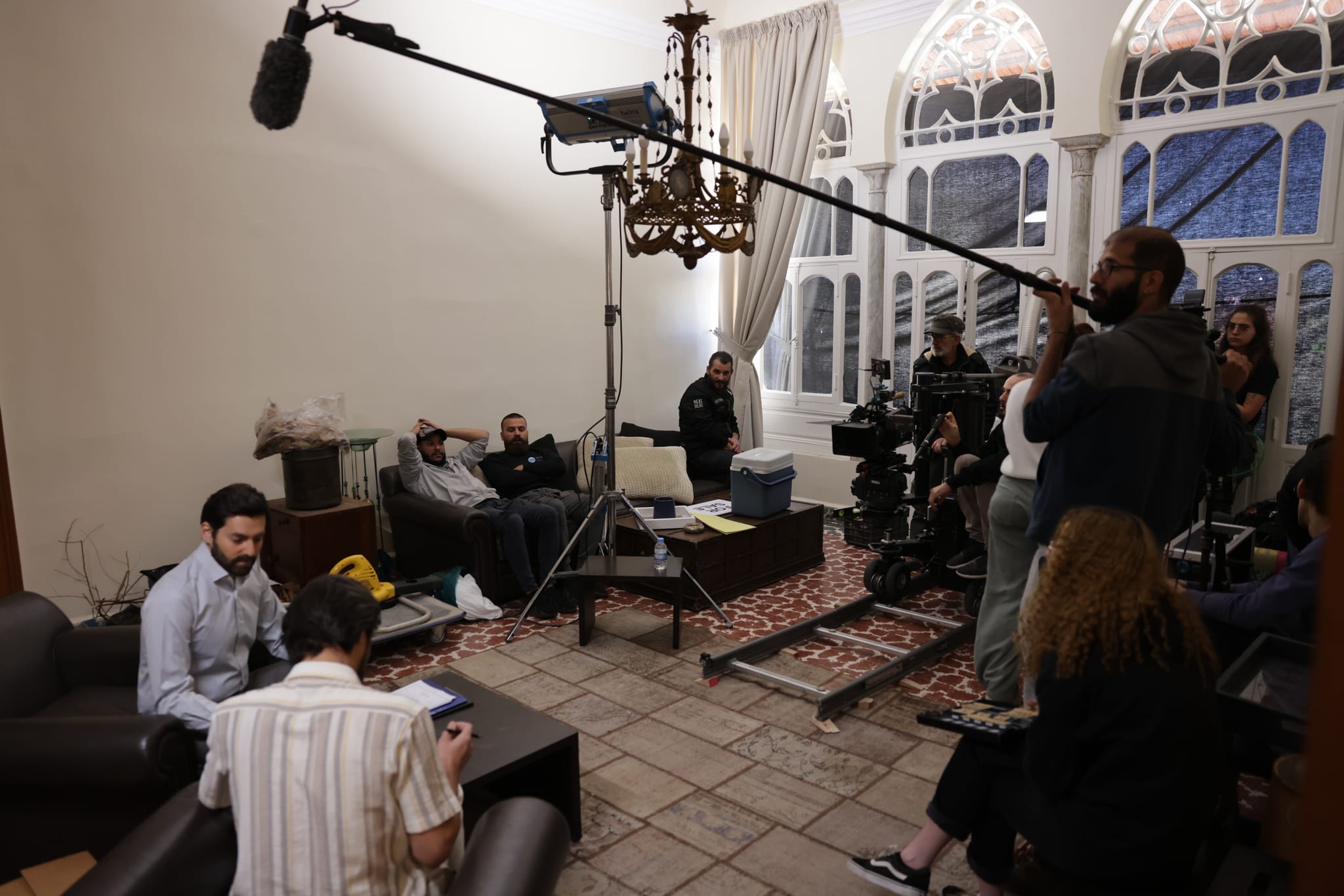 A film crew with a camera dolly and a boom microphone on set in a traditional Lebanese house