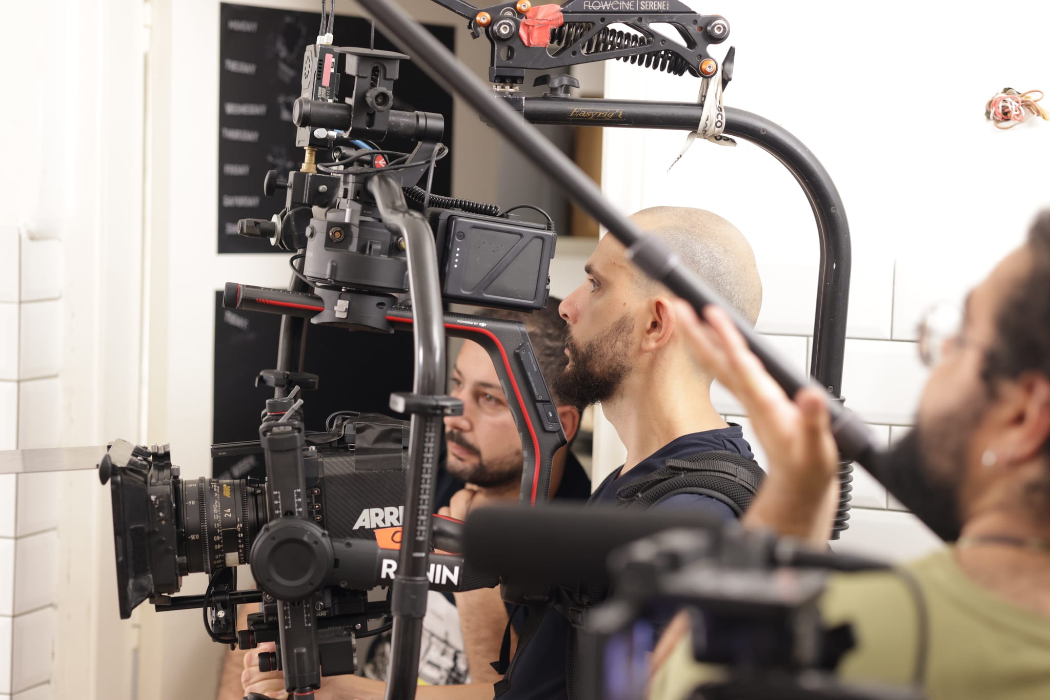 A cinema camera on a stabilising arm, with the camera crew and a boom operator working around it