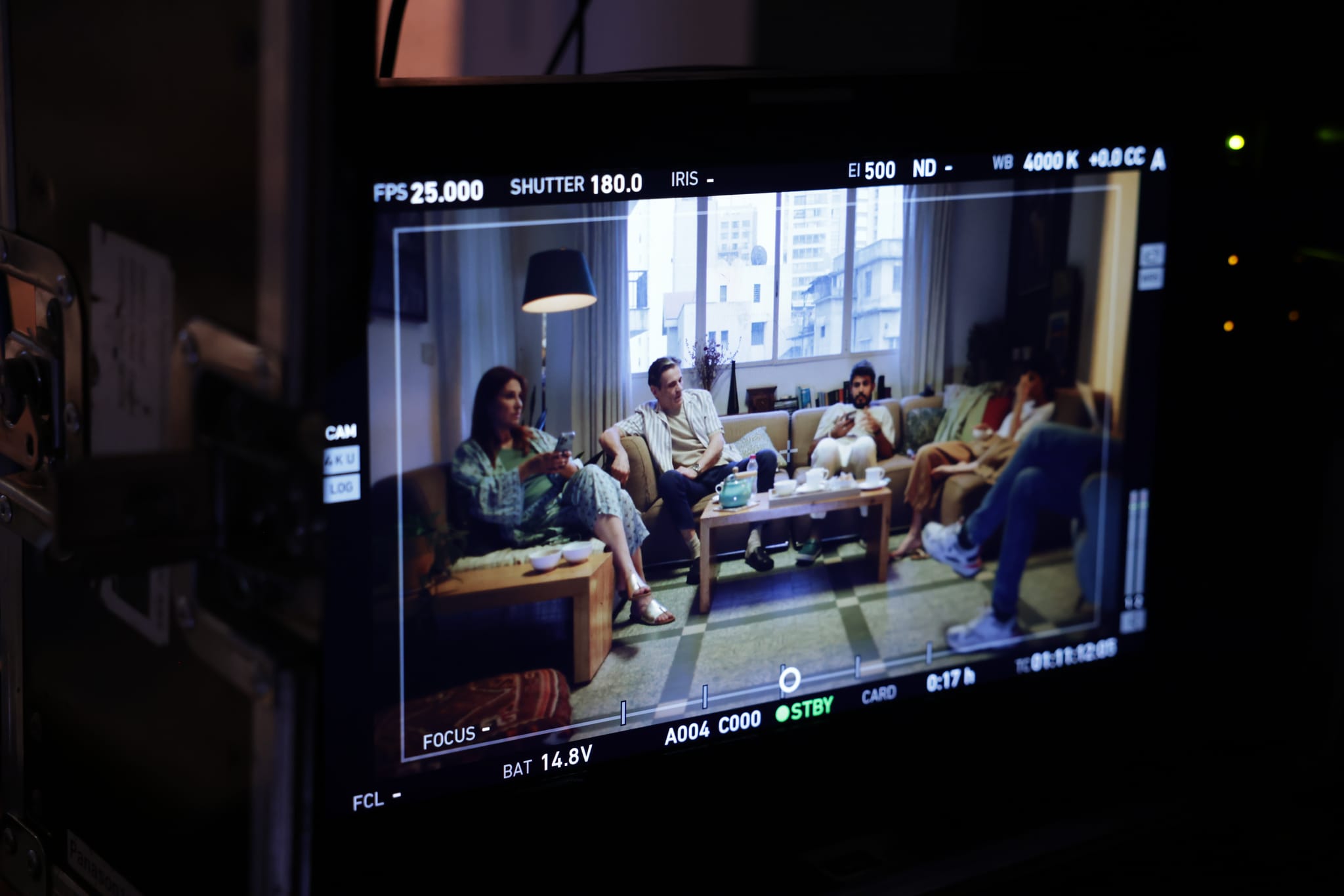 A living-room scene with a group of actors, seen on the camera's monitor