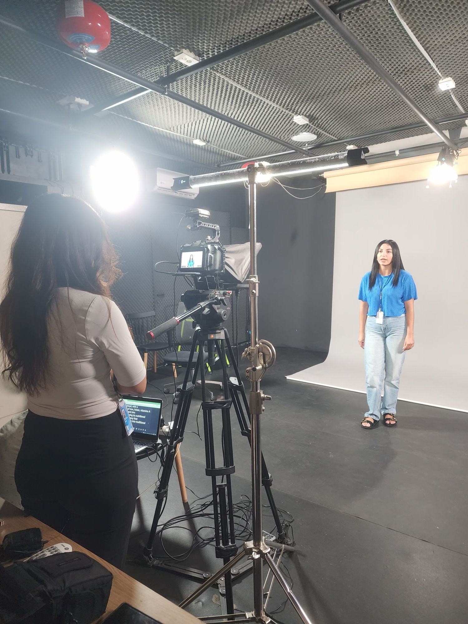 Behind the scenes: presenter on the grey seamless backdrop with teleprompter