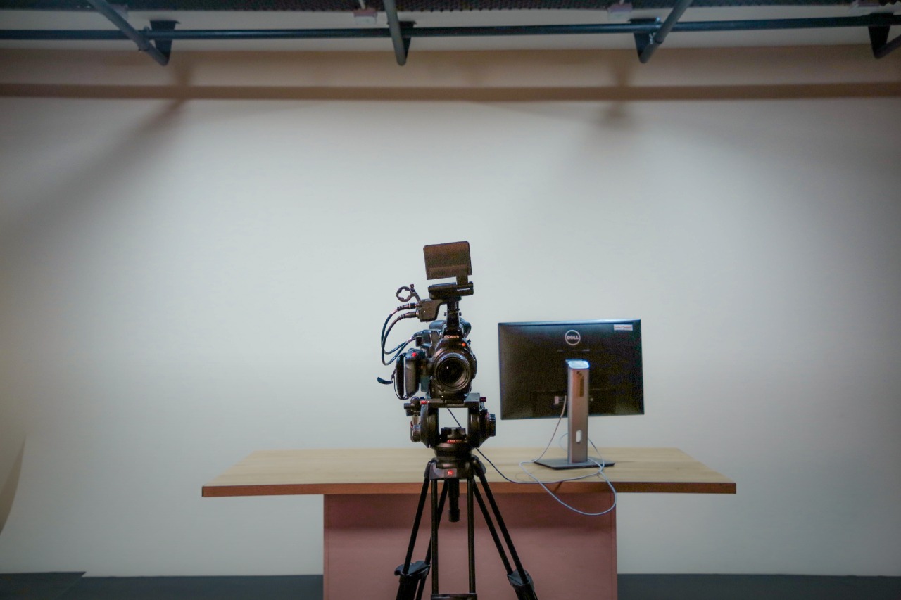 Camera and monitor set up in front of the studio's white wall